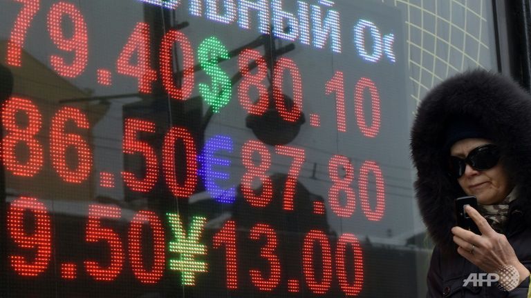 S A woman walks past a board listing foreign currency rates against the Russian rouble in Moscow. Enlar